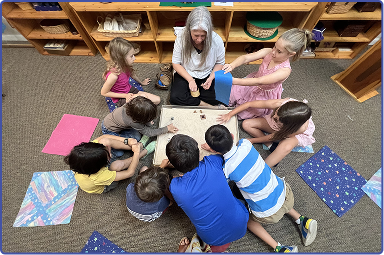 group of children with seated grownup on floor learning