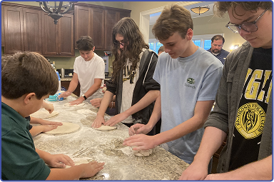 group of teenagers making bread dough in kitchen